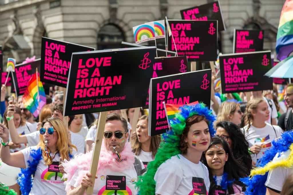 Crowds of people holding 'Love is a human right' Amnesty International signs. 